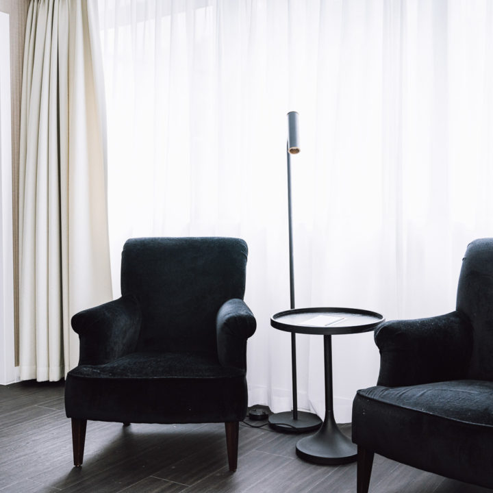 Two black chairs in front of white drapes