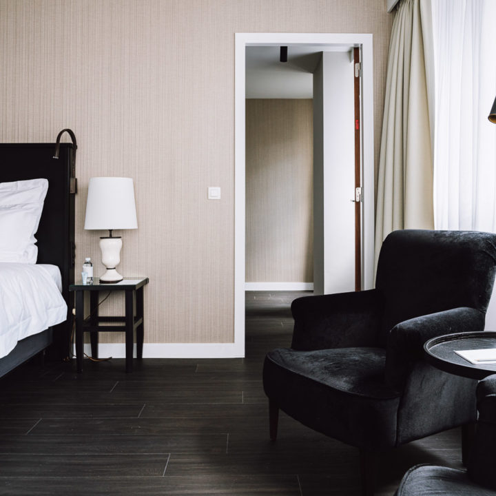 A kingsize bed with a black chari in a hotel room in Pillows Hotel Brussels Centre