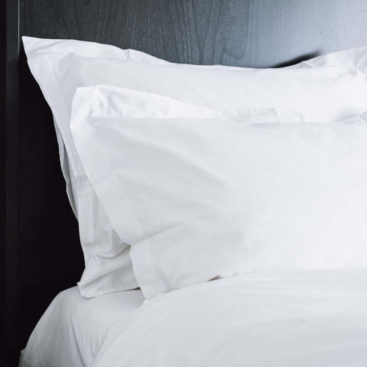 Two fluffy pillows on a bed in a hotel room