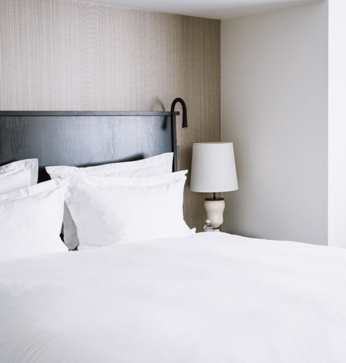 A bed with white sheets in a hotel room in Pillows Hotel Brussels Centre