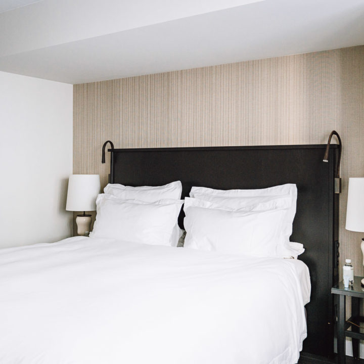 A king size bed with white sheets in a hotel room