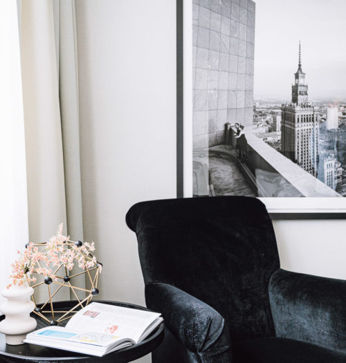 A black chair with a framed picture in a hotel room