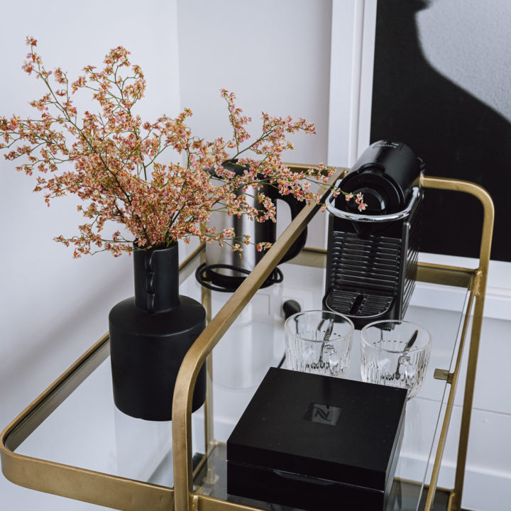 A brass with glass display with flowers and a Nespresso coffeemaker
