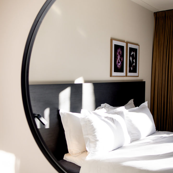Mirror with reflection of a hotel room at Pillows Hotels Deventer