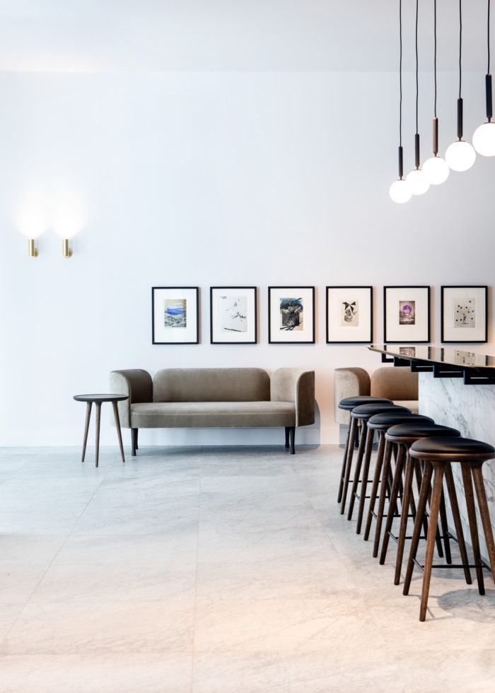 A hip coffee cafe in Ghent with a marble bar and black bar stools