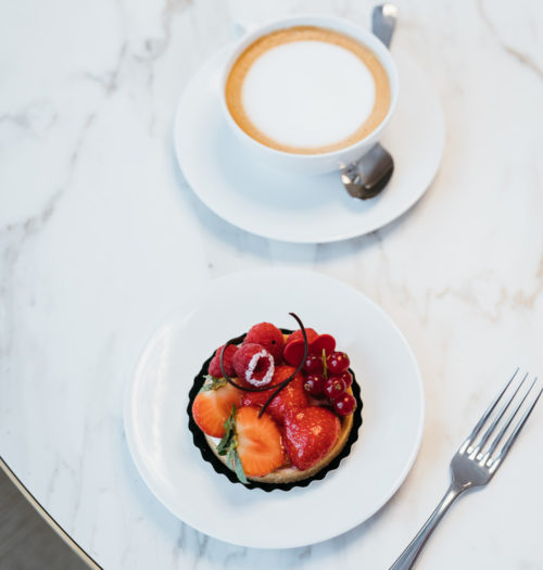 A pastry on a marble table with a cup of coffee