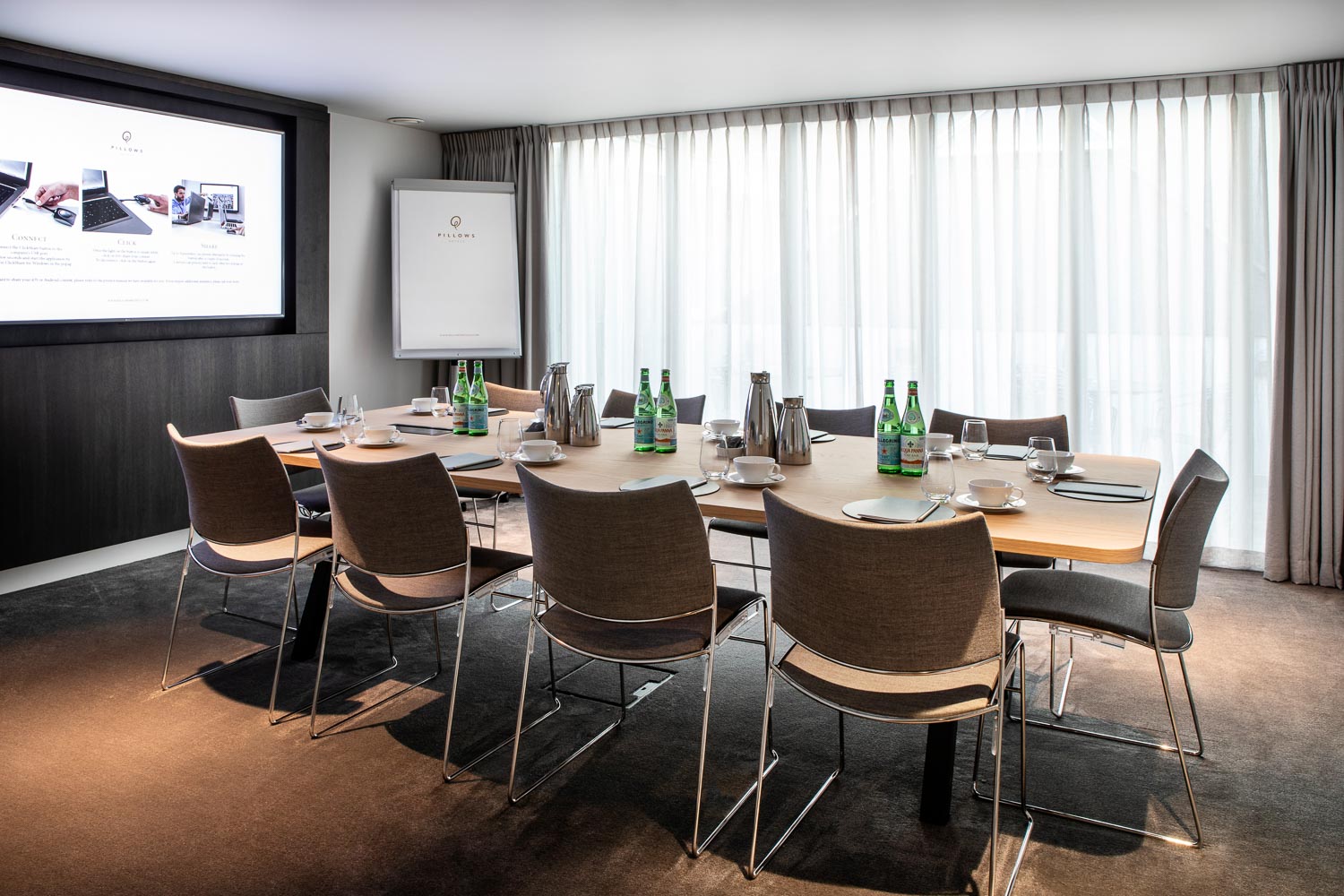A bright meeting room table with grey chairs in Pillows Hotel Reylof in Ghent