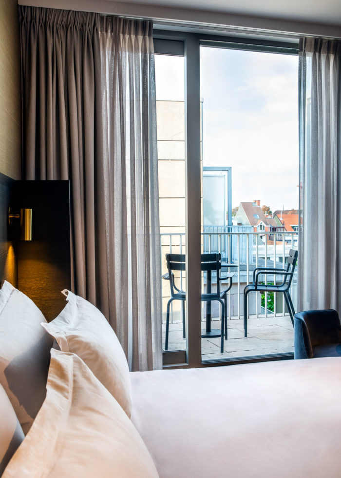 A hotel room with a balcony with two black chairs