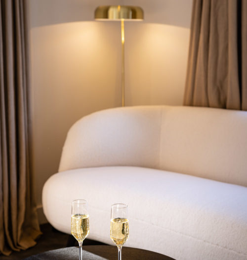 Witte teddy bank in suite met glazen champagne op een donkere tafel