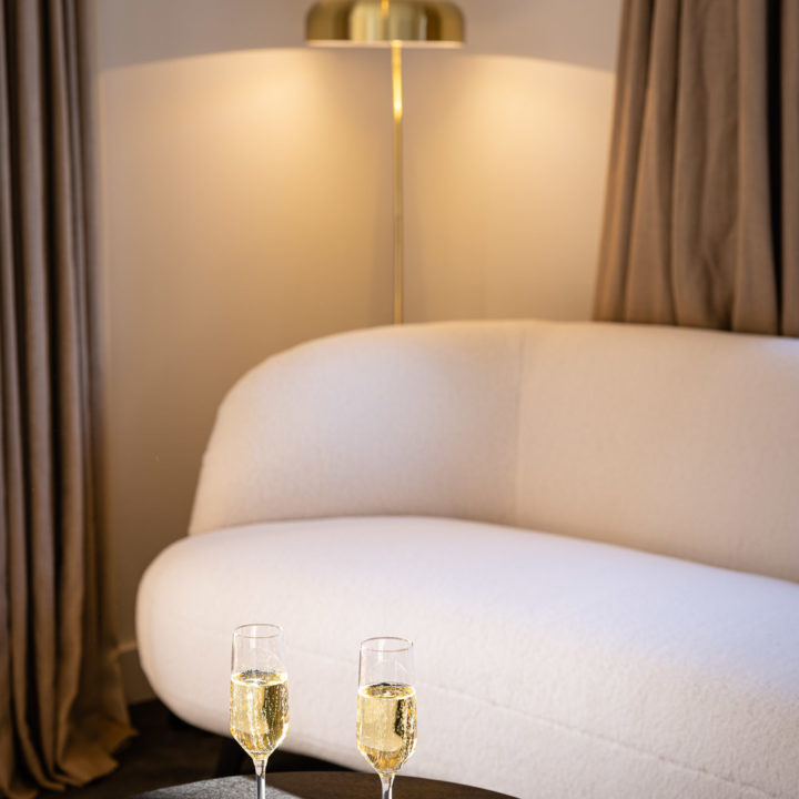 Witte teddy bank in suite met glazen champagne op een donkere tafel